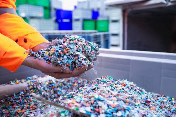 Hands holding shredded multicolour plastic flakes