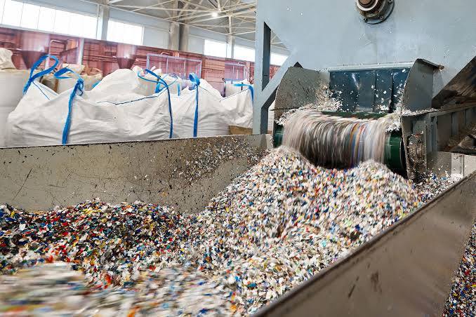Shredded plastic pouring onto a conveyor from the shredder