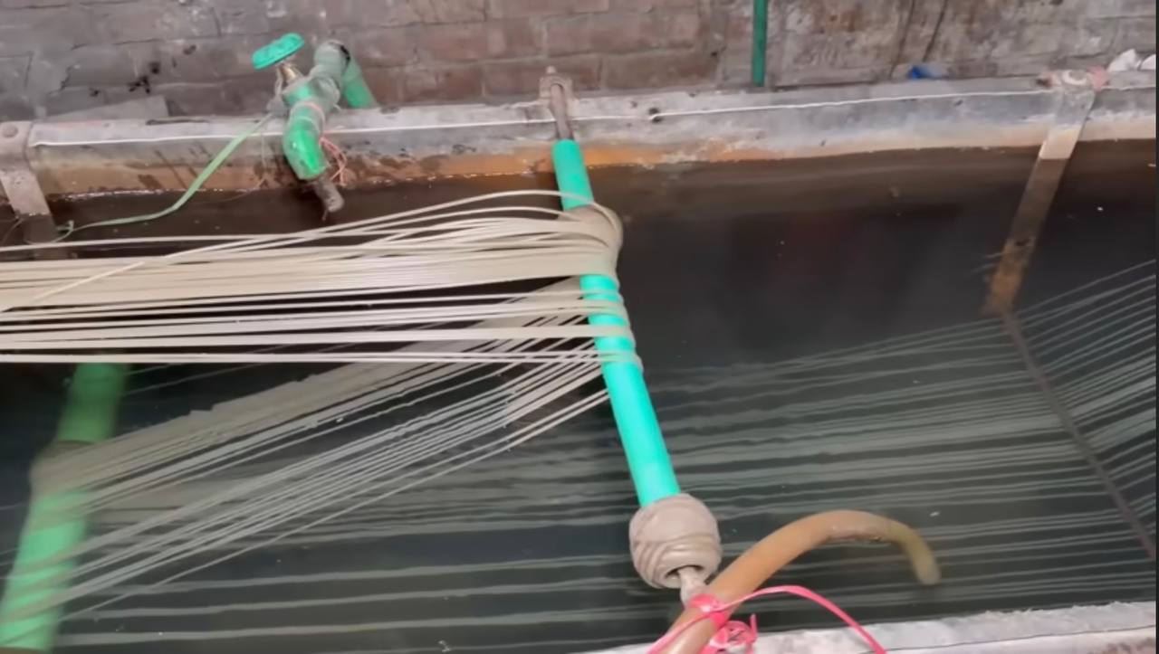 Extruded plastic strands passing through the cooling water bath